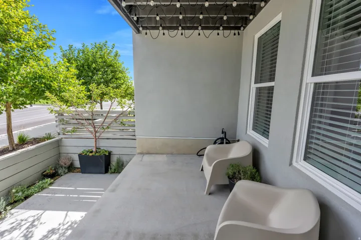 Covered patio with string lighting, stucco exterior, and white-framed windows