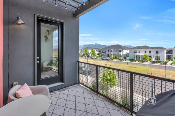 Outdoor balcony with dark gray wall, glass-paned door, and black metal railing