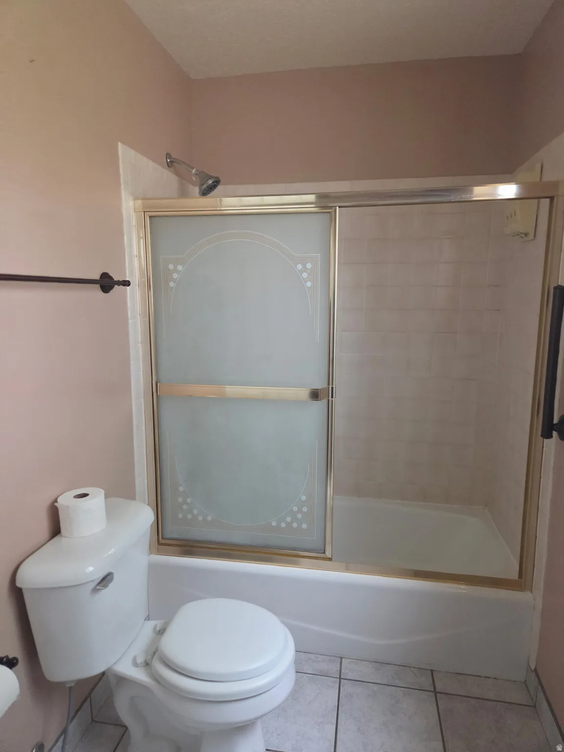 Bathtub with sliding glass shower doors, full tile surround, and white toilet