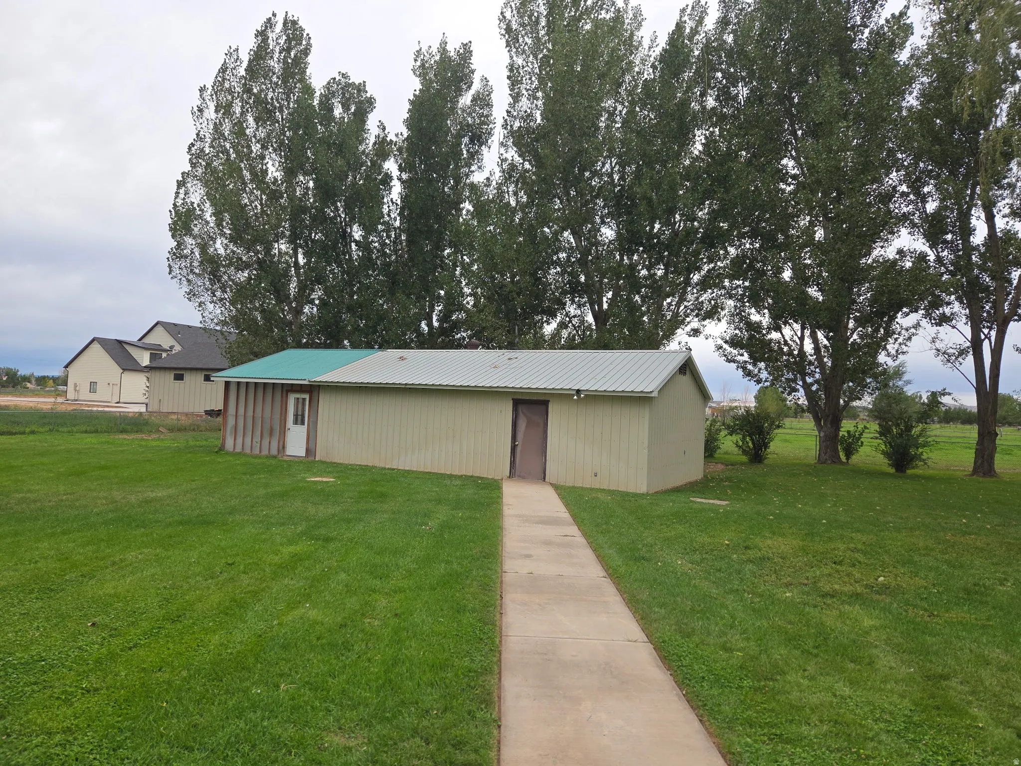 Detached outbuilding with metal siding and a partial green metal roof