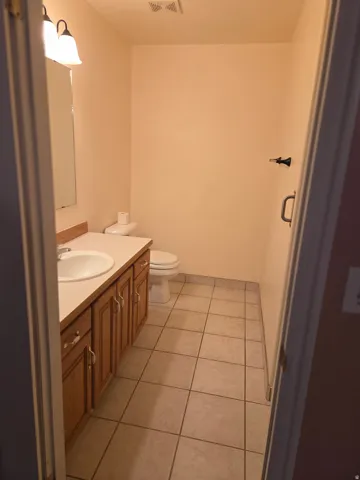 Vanity with wood-finish cabinetry, integrated sink, and wall-mounted lighting