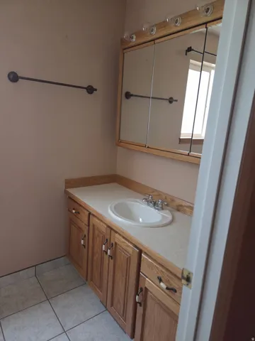 Wood-finish vanity with integrated sink, chrome faucet, and ample storage cabinetry