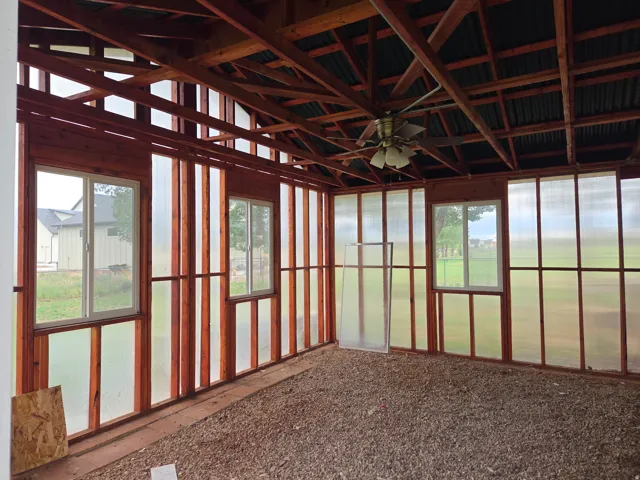 Open-beamed ceiling structure with exposed rafters, corrugated roofing, and a ceiling fan
