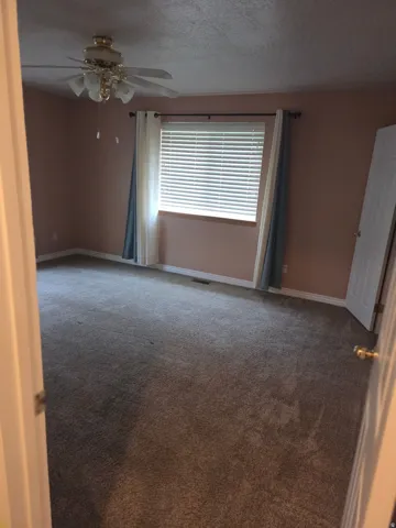 Room featuring wall-to-wall carpeting, a window with blinds, and a ceiling fan