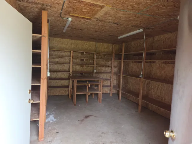 Built-in shelving units, concrete flooring, overhead fluorescent lighting, and plywood walls