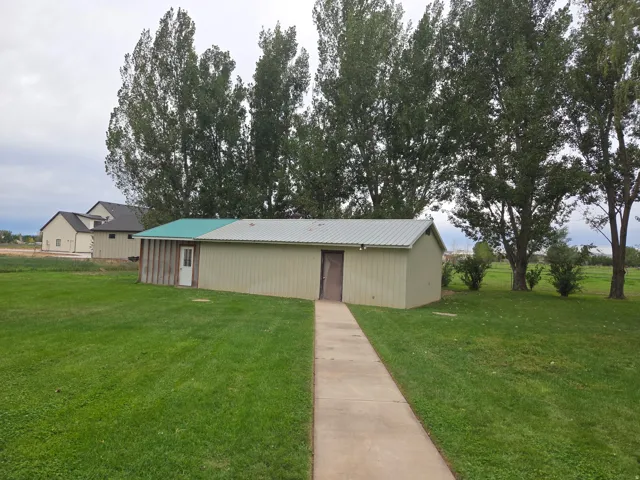 Detached outbuilding with metal siding and a partial green metal roof