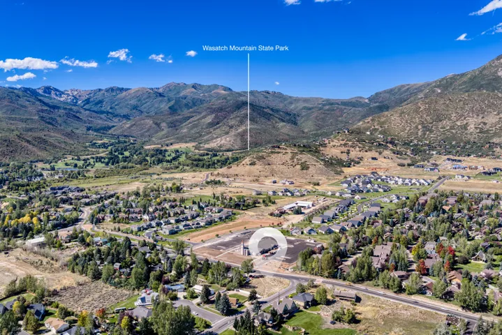 Mountainous terrain backdrop, residential community, road infrastructure, green spaces, clear blue sky