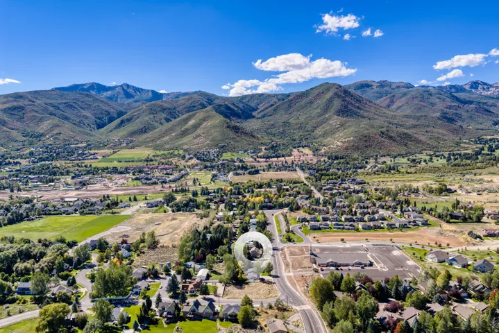 Expansive mountain scenery, suburban neighborhood setting, residential roads, surrounding green spaces, distant commercial structures