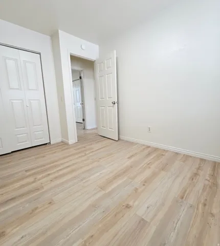 Wood-finish flooring throughout, bright white walls, and a built-in closet with bifold doors