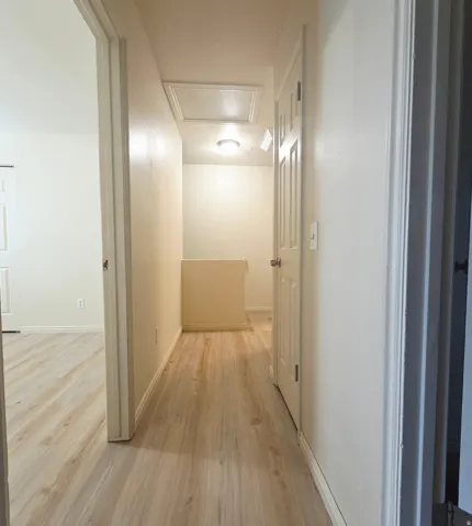 Wood-finish flooring throughout, white walls, and a recessed ceiling light fixture