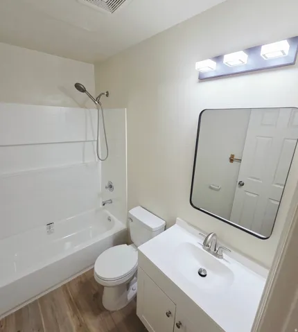 White vanity with integrated sink, chrome faucet, and rectangular mirror