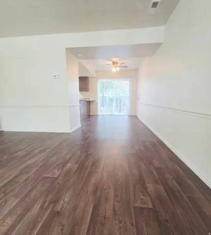 Wood-finish flooring throughout, white walls with chair rail molding, and a sliding glass door with vertical blinds