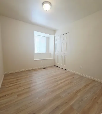 Wood-finish flooring, recessed window ledge, white trim, and bi-fold closet doors
