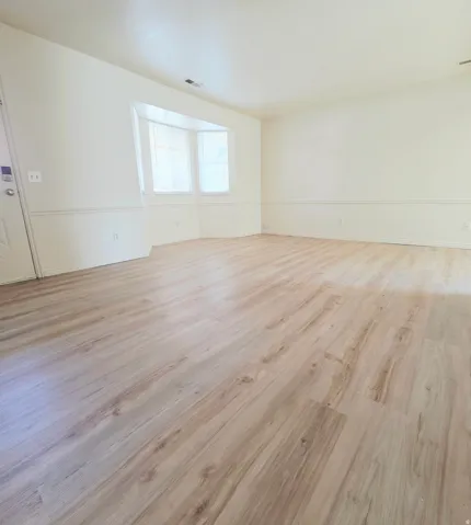 Wood-finish flooring, bay window, white interior door, and wainscoting
