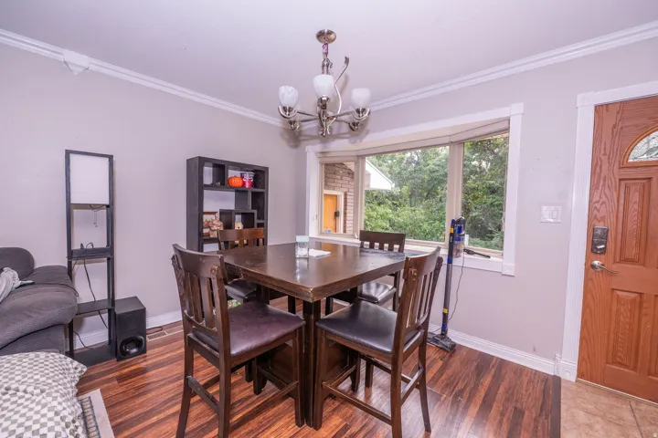 Bay window with white trim, wood-finish flooring, and a decorative ceiling light fixture