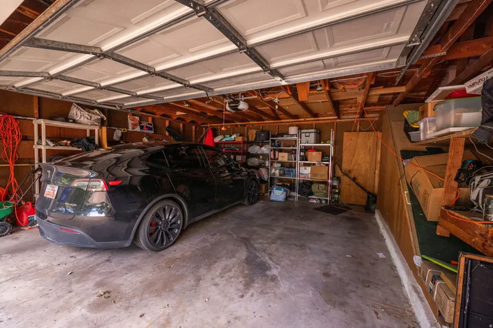 Attached garage with concrete flooring, wood-framed ceiling, and panel garage door