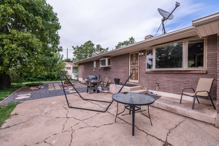 Rear concrete patio with a brick exterior and a gravel-accented garden bed