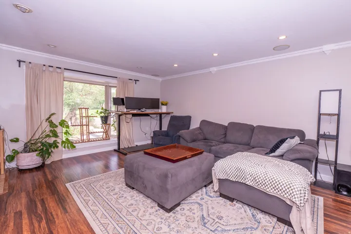 Recessed ceiling lighting, crown molding, wood-finish flooring, and a large window