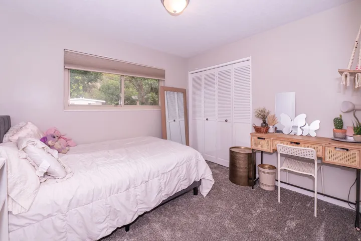 Wall-to-wall carpeting, window with roller shade, and louvered bi-fold closet doors