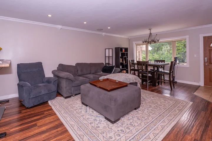 Open-concept living area with wood-finish flooring, recessed lighting, and crown molding