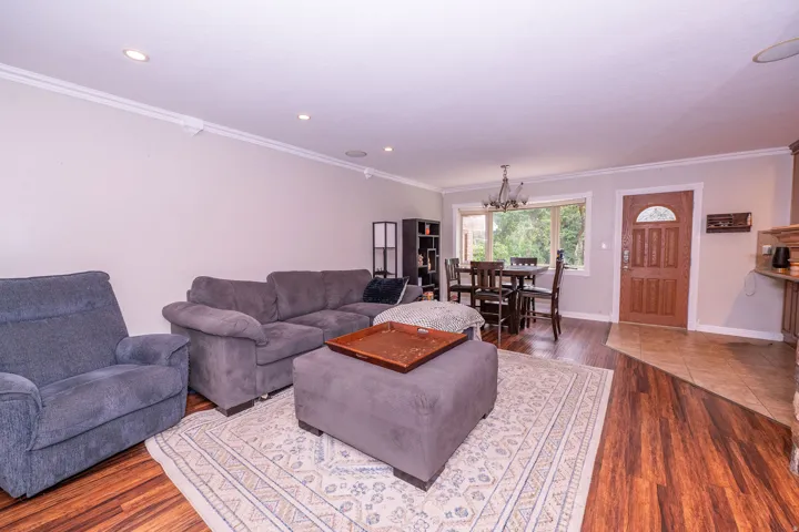 Recessed ceiling lighting, crown molding, wood-finish flooring, and a dining area with a chandelier