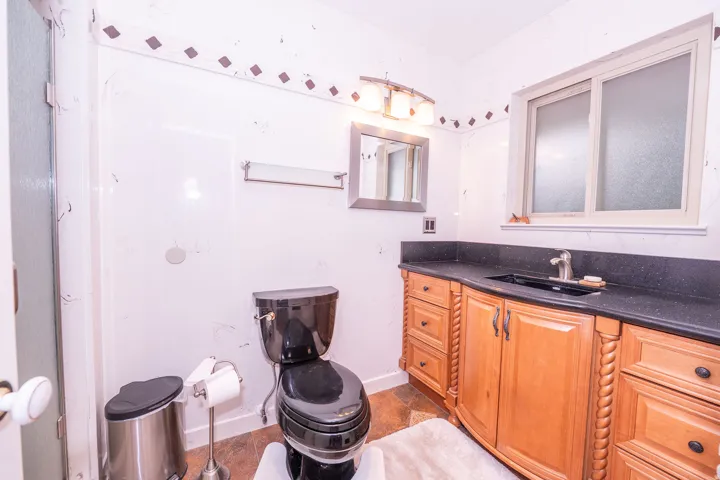 Wood-finish vanity with rope-twist detailing, dark countertop, and integrated sink