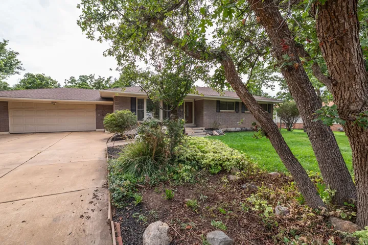 Brick exterior featuring a two-car garage, concrete driveway, and front lawn