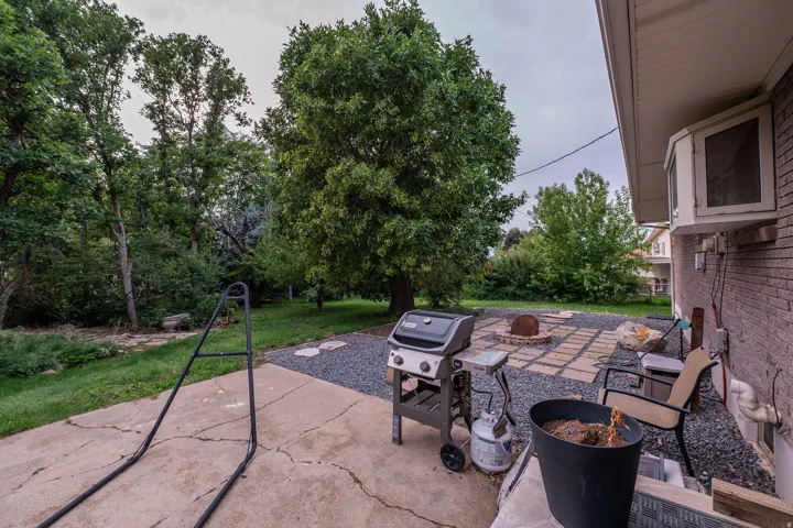 Backyard patio featuring concrete and stone pavers, a gravel hardscape area, and a built-in fire pit