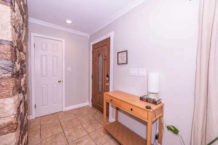 Front entry featuring tile flooring, a solid wood front door with decorative glass, and crown molding