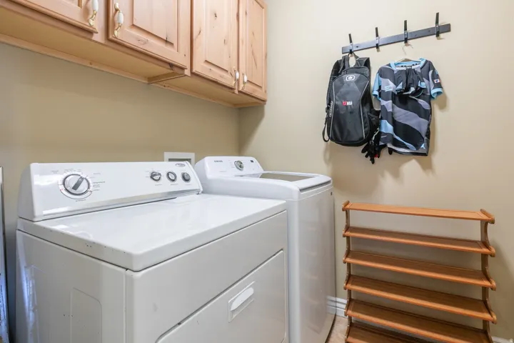 Upper wood-finish cabinetry, neutral wall paint, and white appliances