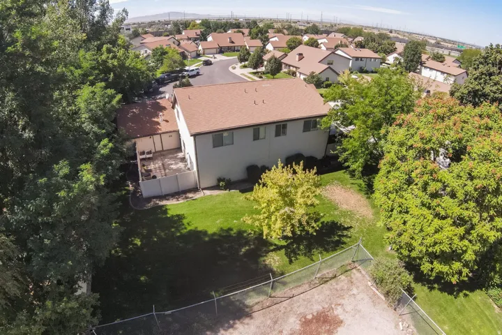 Expansive backyard with a manicured lawn, established trees, and a private patio featuring a white privacy fence