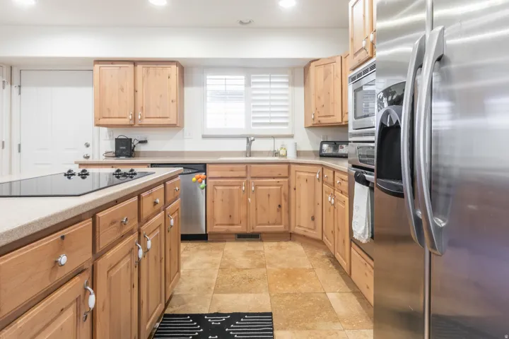 Kitchen featuring wood cabinetry, stainless steel appliances, a built-in cooktop, and tile flooring