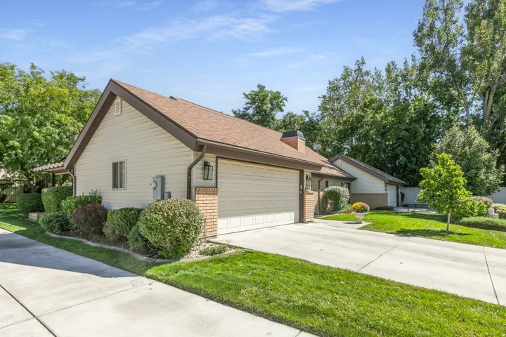 Siding exterior with brick accents, attached two-car garage, concrete driveway, and established landscaping