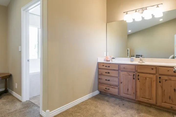 Spacious vanity with light wood cabinetry, a built-in sink, and a large mirror