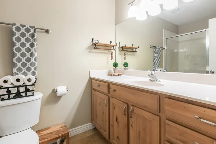 Vanity with wood-finish cabinetry, integrated sink, and full-width mirror