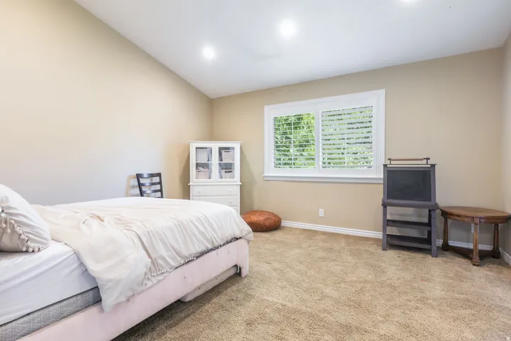 Vaulted ceilings, recessed lighting, neutral wall tones, window with white blinds, and carpeted flooring