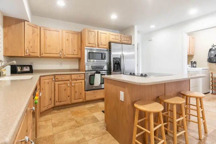 Wood cabinetry with stainless steel appliances, a built-in oven, and a cooktop on the island