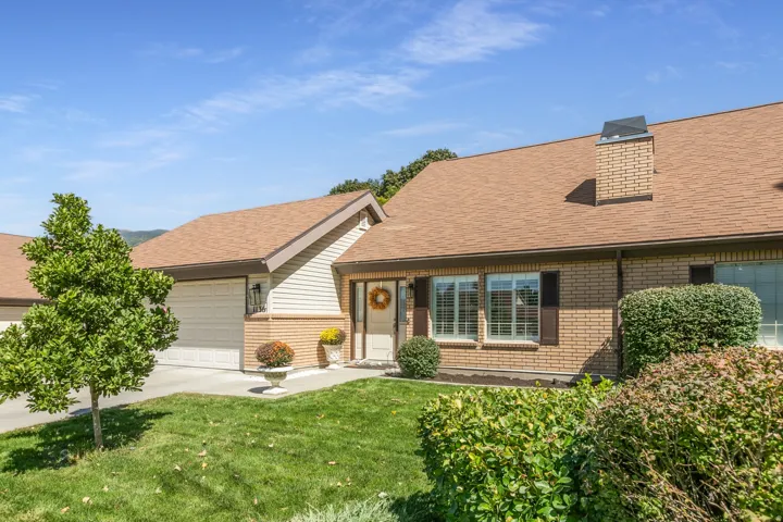 Brick exterior with a prominent chimney, brown asphalt shingle roof, and a two-car garage
