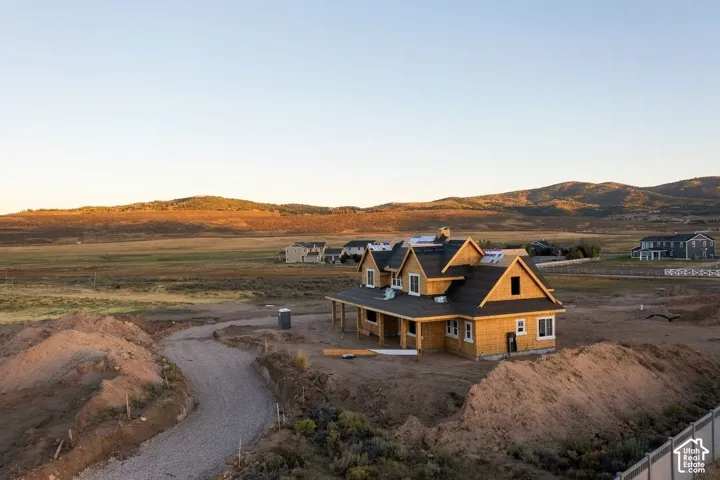 Multi-gabled structural framing featuring a wraparound covered porch, wood-frame construction, and prominent mountain backdrop