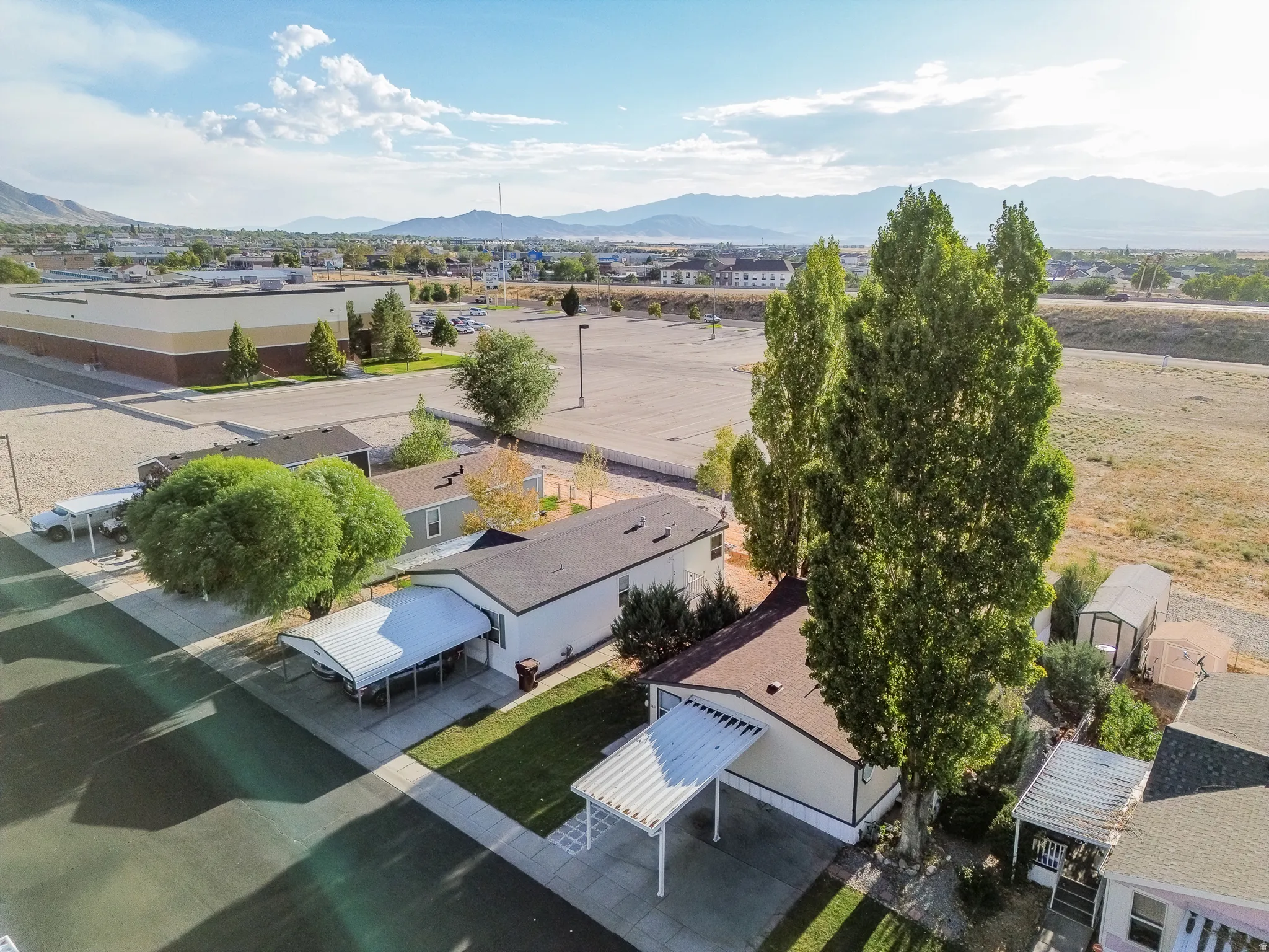 Manufactured home with covered carport, mature trees, and a landscaped front yard