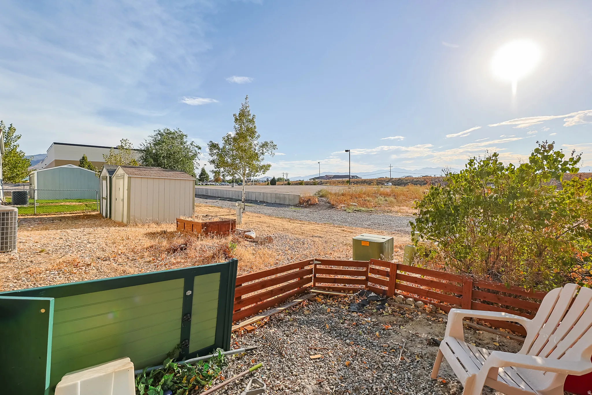 Gravel ground cover with a low wooden fence and two storage sheds