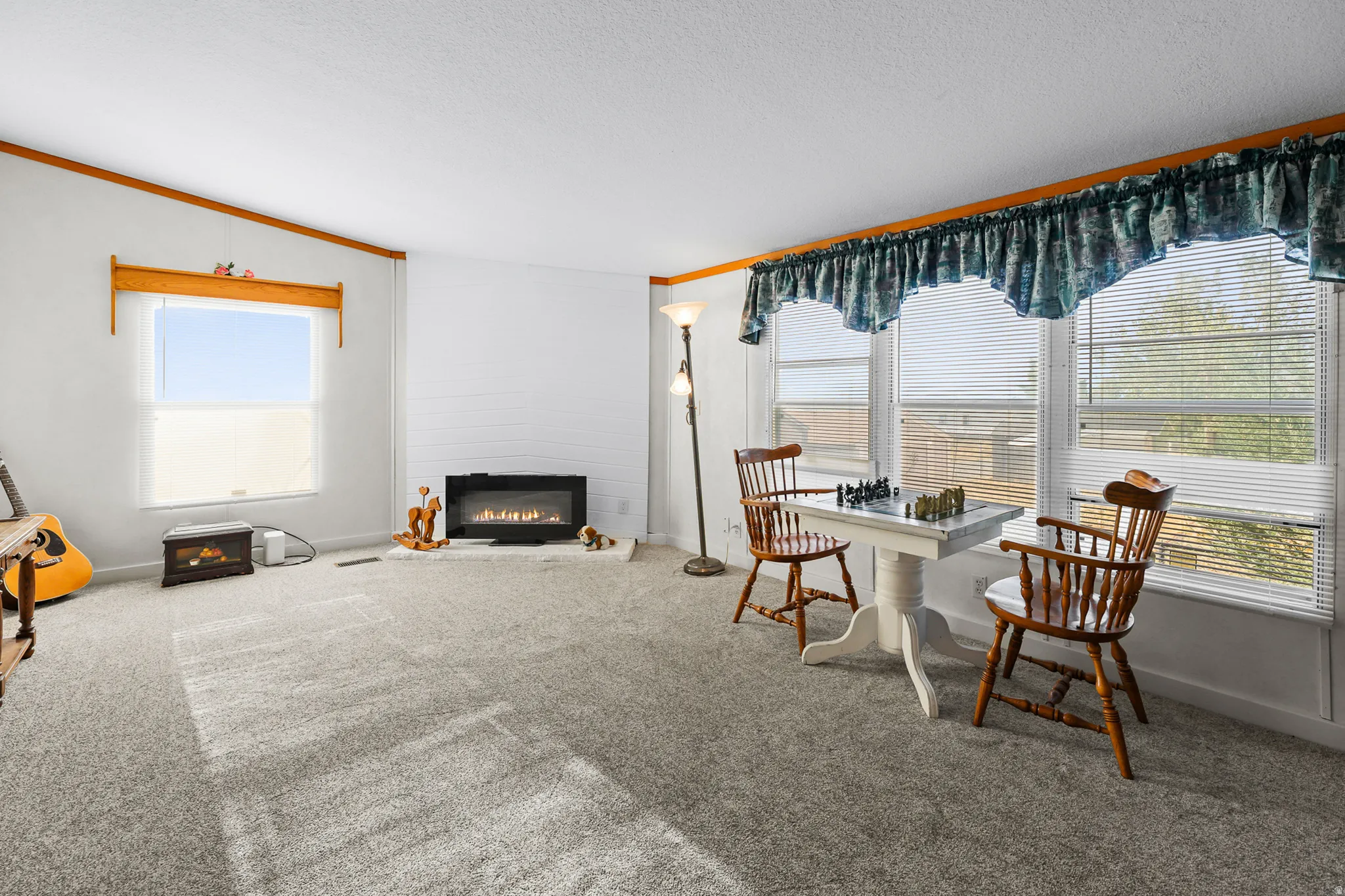 Carpeted living area featuring multiple windows, a built-in electric fireplace, and white painted walls