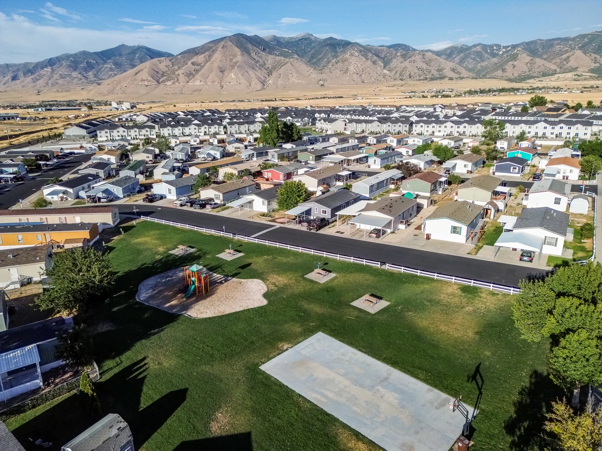 Expansive green space with a playground area and hard surface recreation court