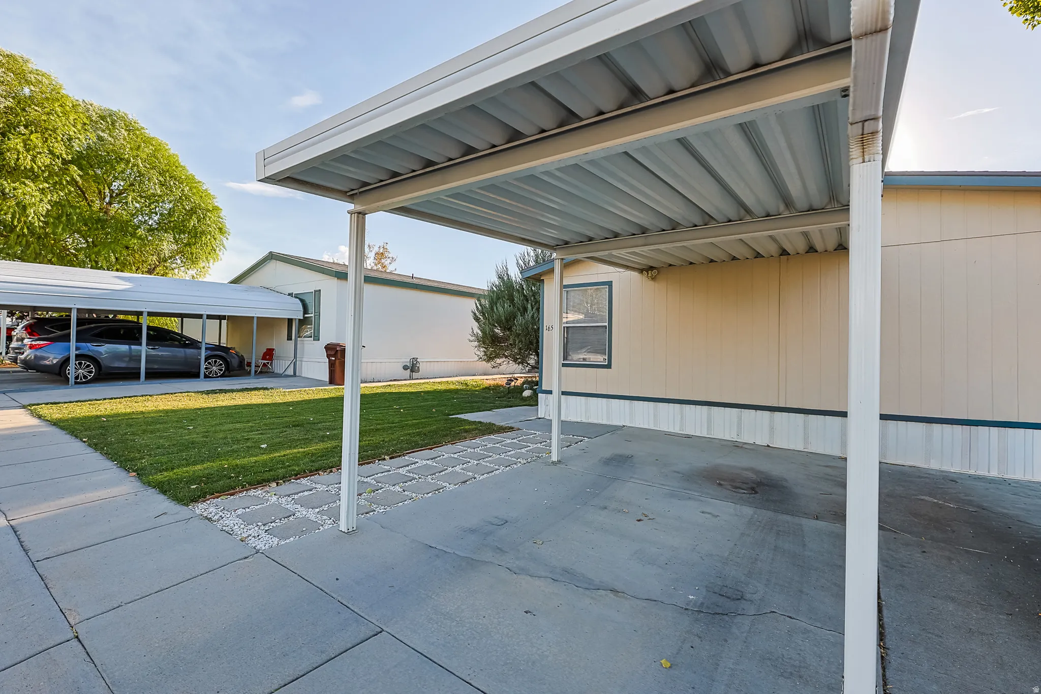 Covered carport with a concrete drive, siding exterior, and a manicured lawn