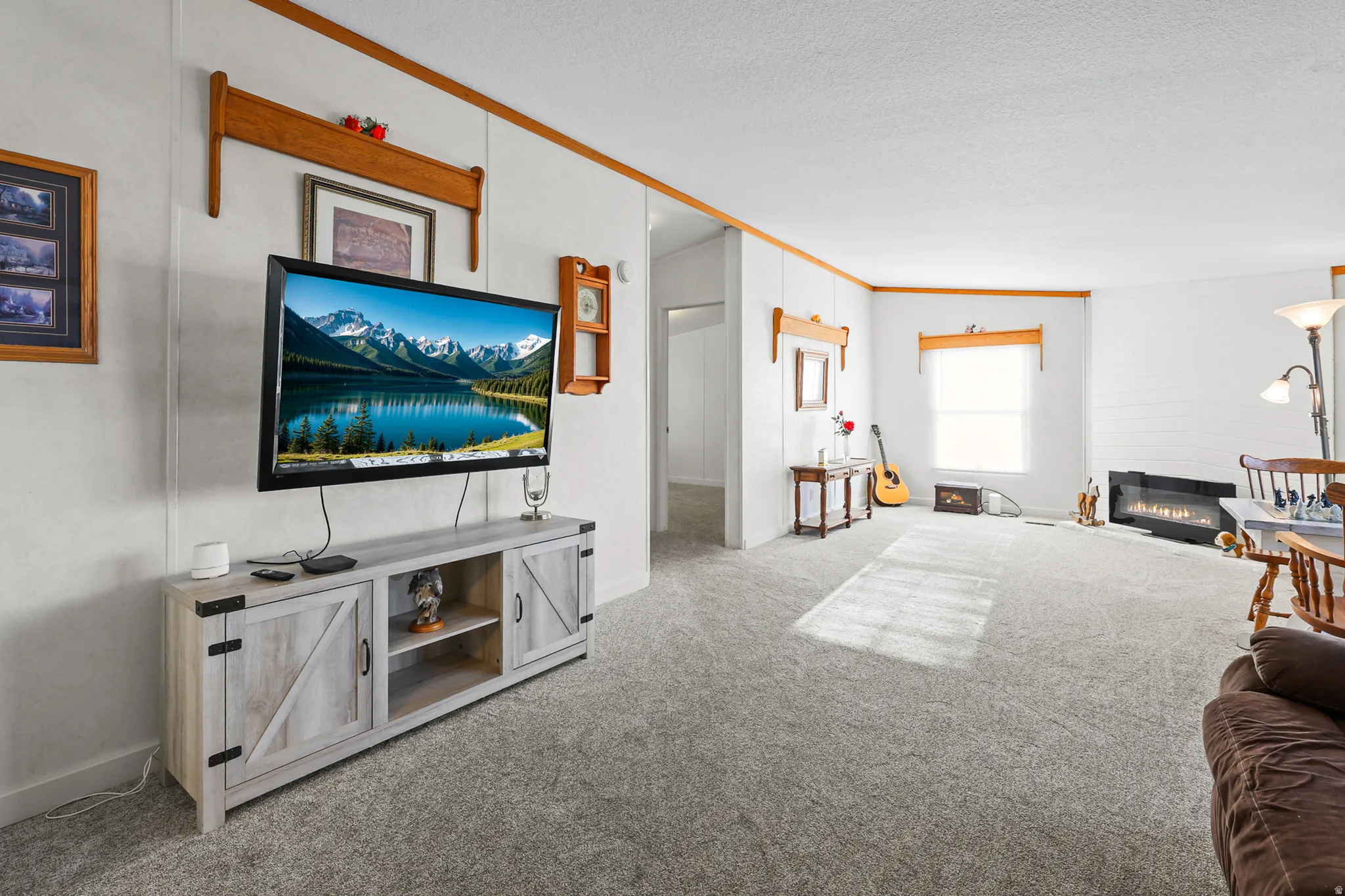 Recessed lighting, wood-finish trim, plush carpeting, and a modern wall-mounted fireplace