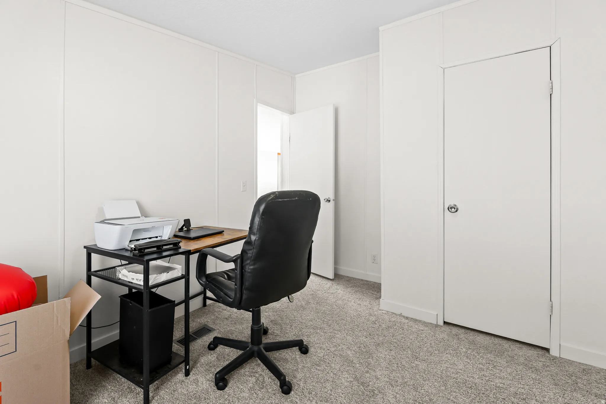Textured wall panels, light-colored carpeting, two white doors, and a ceiling with a textured finish
