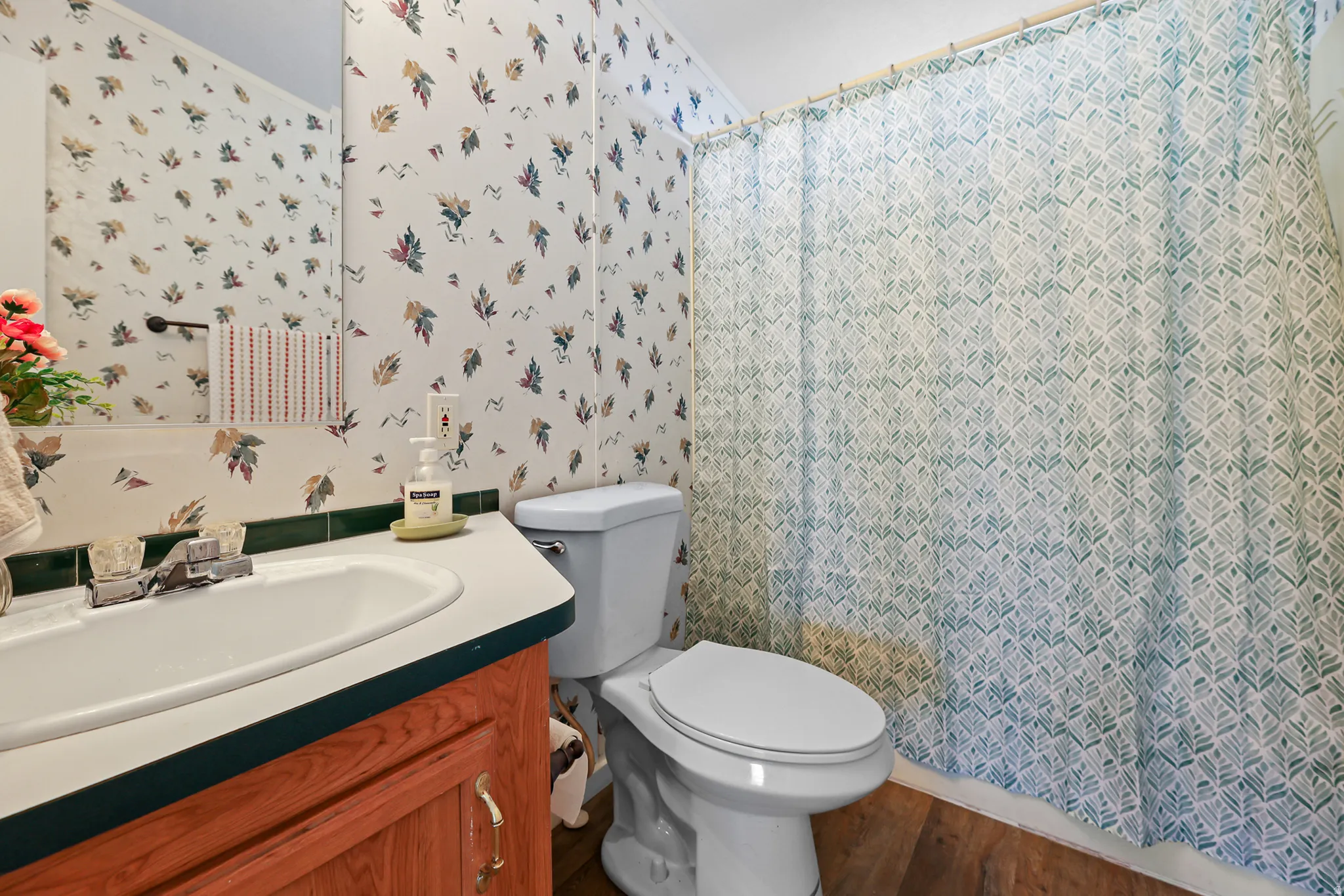 Bathroom featuring a vanity with an integrated sink, a toilet, a full-width mirror, and wood-finish flooring