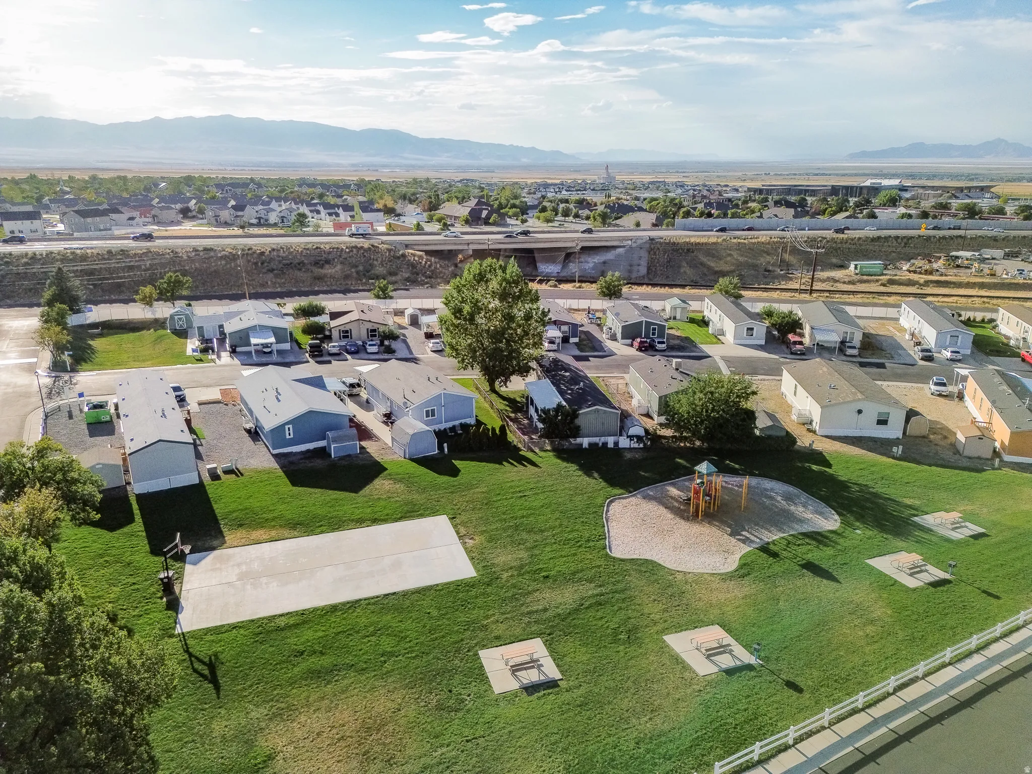 Community green space featuring a playground, concrete activity pad, and picnic areas
