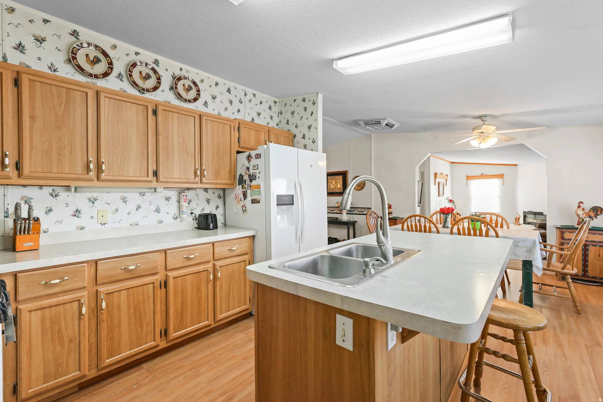 Kitchen featuring light wood-finish cabinetry, light countertops, wood-finish flooring, and a stainless steel double-basin sink