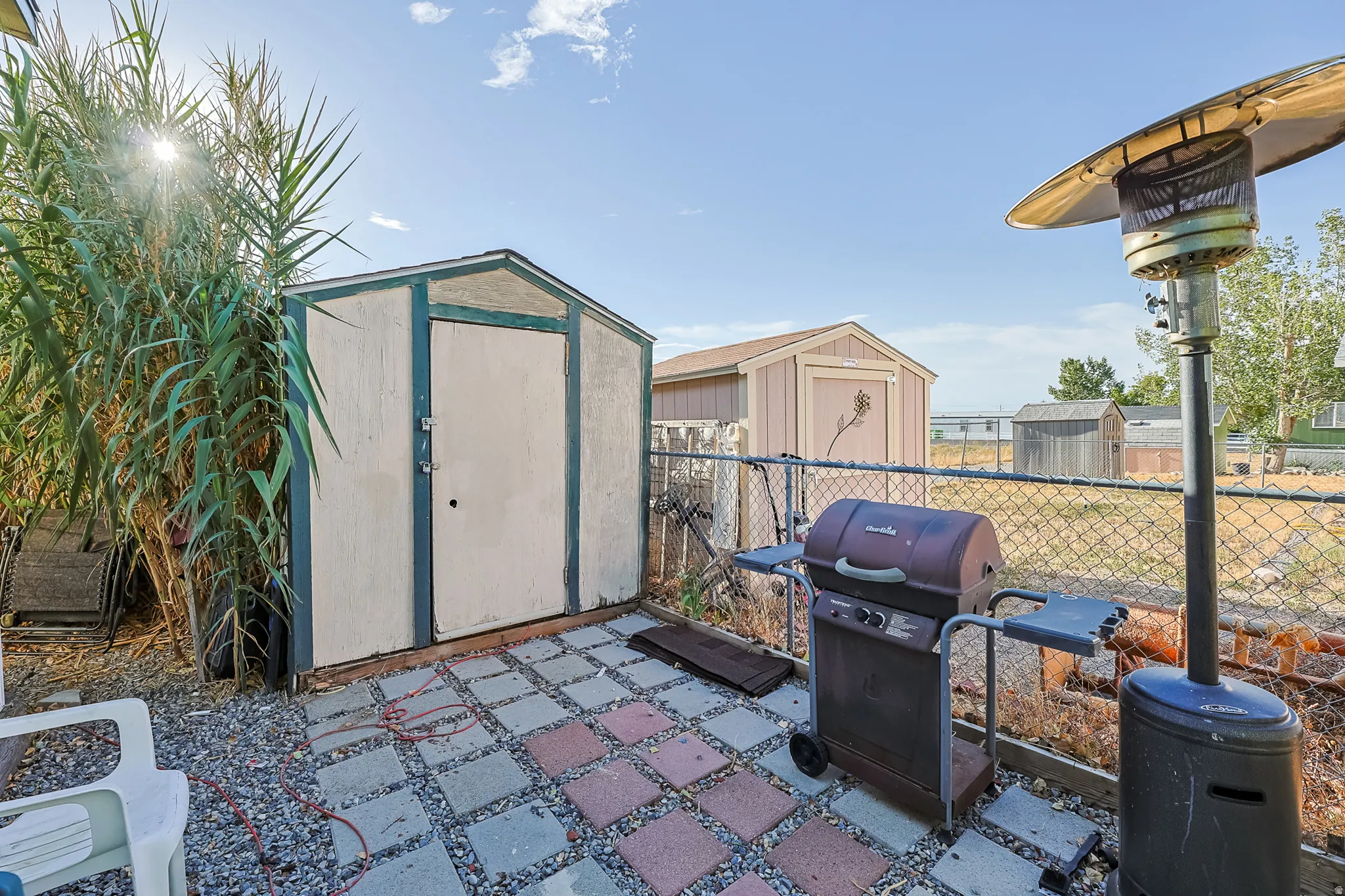 Paved patio area featuring a storage shed and chain-link fencing
